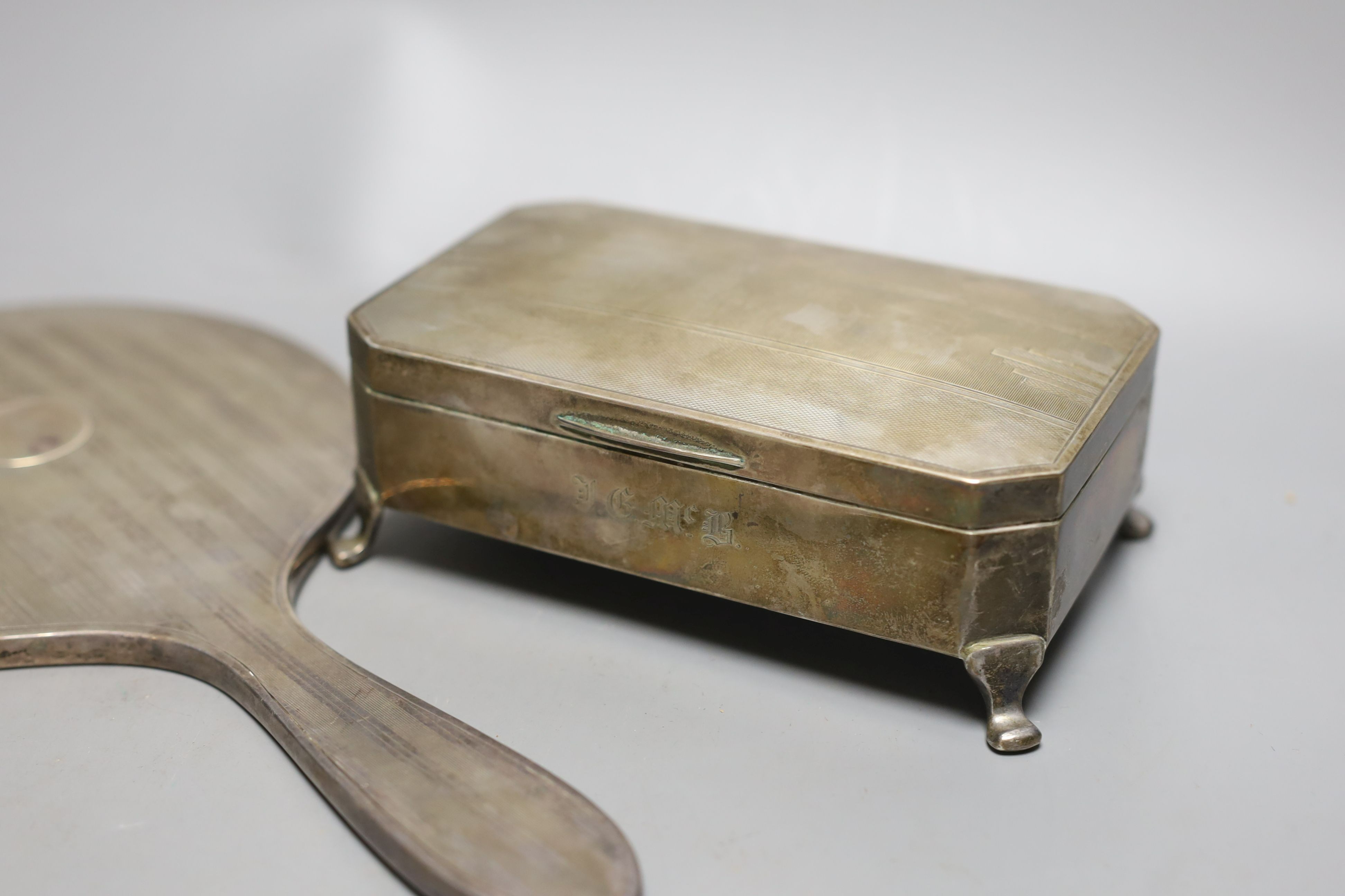 An Art Deco silver mounted cigarette box, a silver cigarette box, silver trinket box and a silver mounted hand mirror.